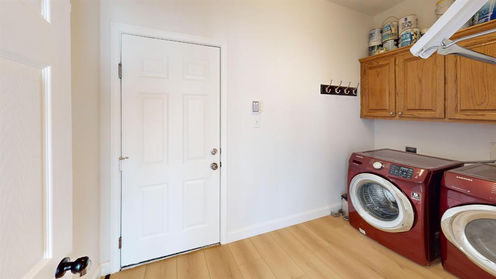 Laundry room featuring wood-finish flooring, wall-mounted cabinetry, and a multi-hook rack