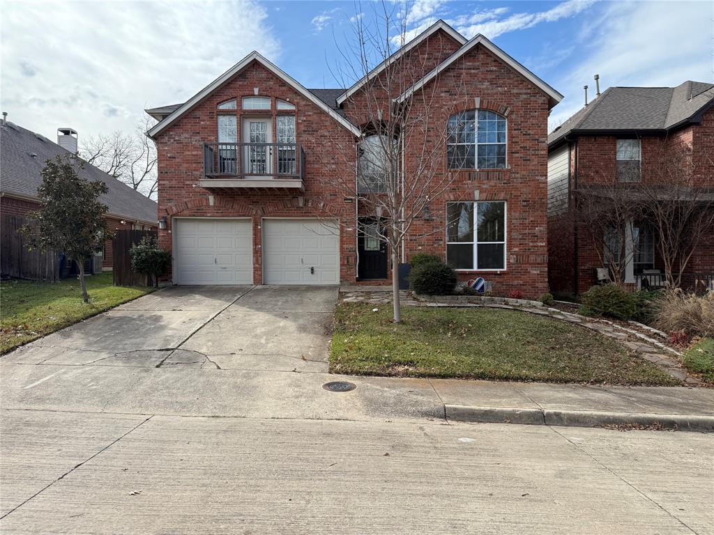 Two-story brick exterior featuring a second-story balcony, arched window detailing, and a two-car garage Two-story brick exterior featuring a second-story balcony, arched window detailing, and a two-car garage