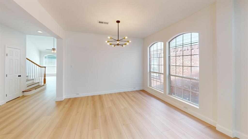 Wood-finish flooring, multi-light modern chandelier, and arched grid windows