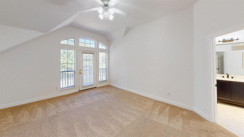 Vaulted ceilings, carpeted flooring, multi-pane glass door with surrounding windows, and integrated ceiling fan