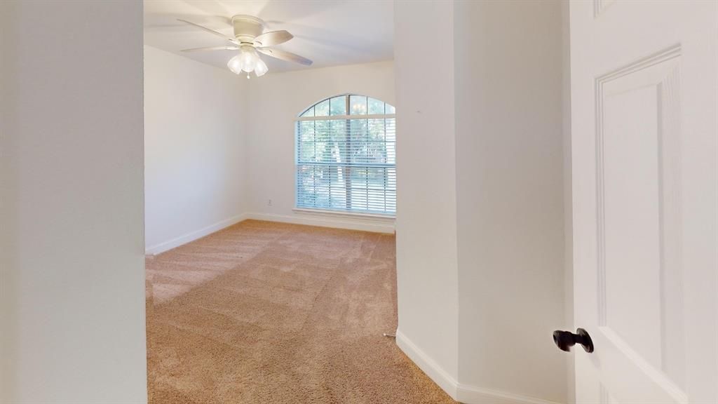 Room featuring neutral wall-to-wall carpeting, an arched window with horizontal blinds, and a ceiling-mounted light fixture with a central fan