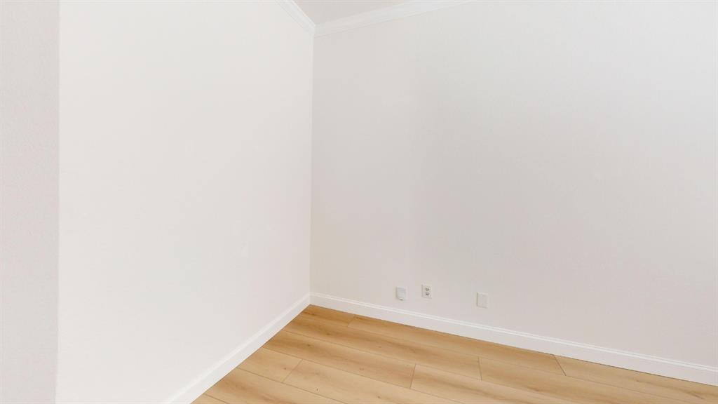Interior space featuring neutral wall tones, crown molding, and wood-finish flooring