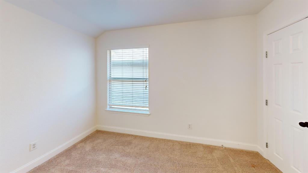 Room featuring neutral-toned carpeting, off-white wall finishes, a single-pane window with horizontal blinds, and a white interior door with dark hardware