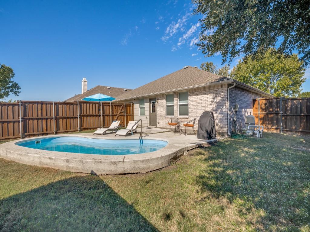 Exterior space featuring a concrete-encased pool, a paved patio, and perimeter wood privacy fencing