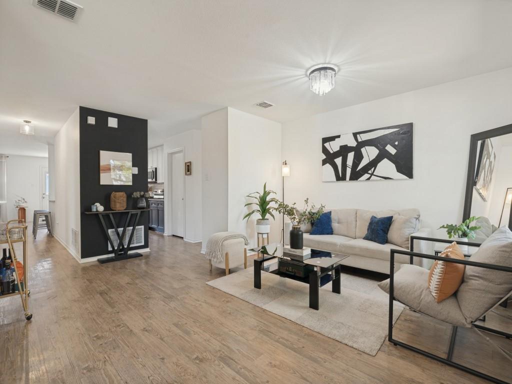 Living space featuring wood-finish flooring, a contemporary crystal flush-mount light fixture, and a distinct black accent wall