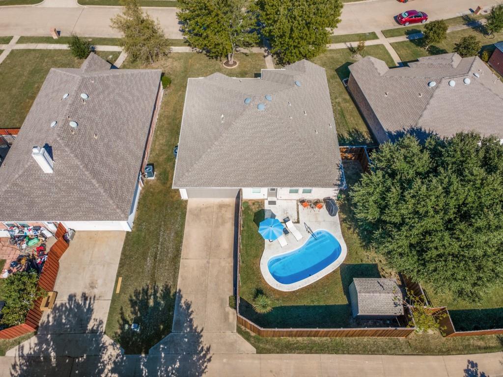 Aerial perspective of a property featuring an in-ground swimming pool, concrete patio, fenced backyard, and a detached storage shed