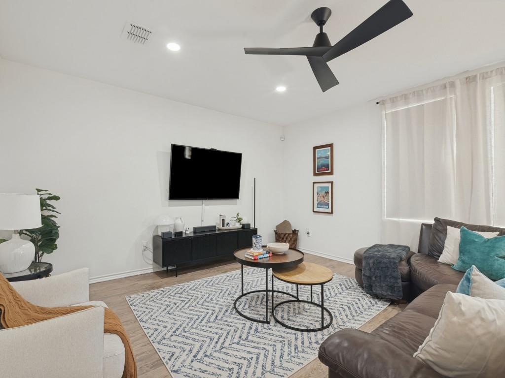 Modern matte black ceiling fan, recessed lighting, and wood-finish flooring