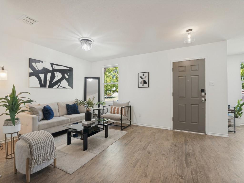 Wood-finish flooring, neutral wall palette, multi-paneled entry door, crystal-accent flush mount lighting, and recessed ceiling lighting