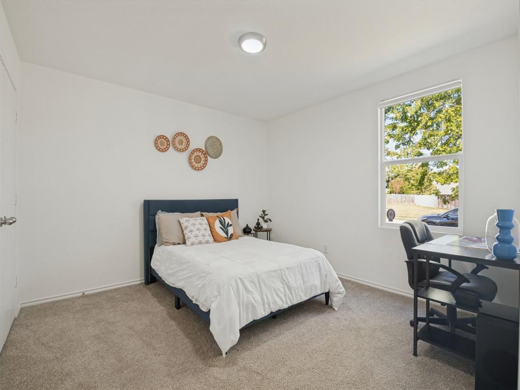 Neutral-toned carpeting, high-gloss white walls, single-hung window with exterior greenery, flush-mount ceiling light fixture, and interior door with brushed metal hardware