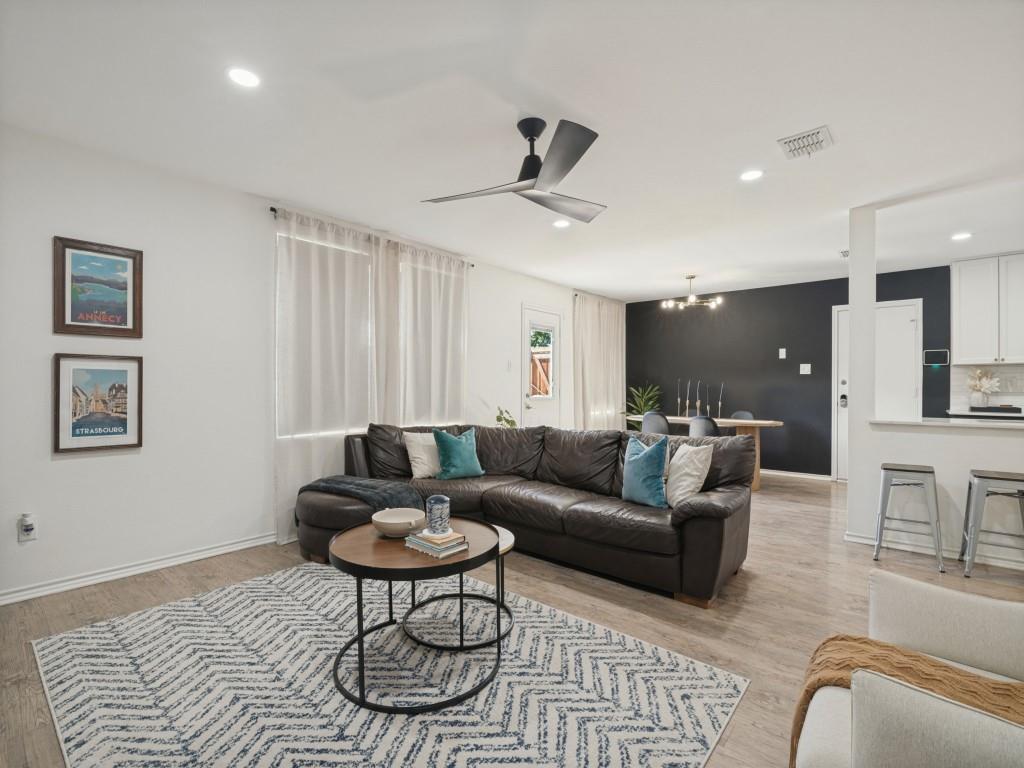 Open-concept interior featuring wood-finish flooring, recessed lighting, a matte black ceiling fan, and a breakfast bar