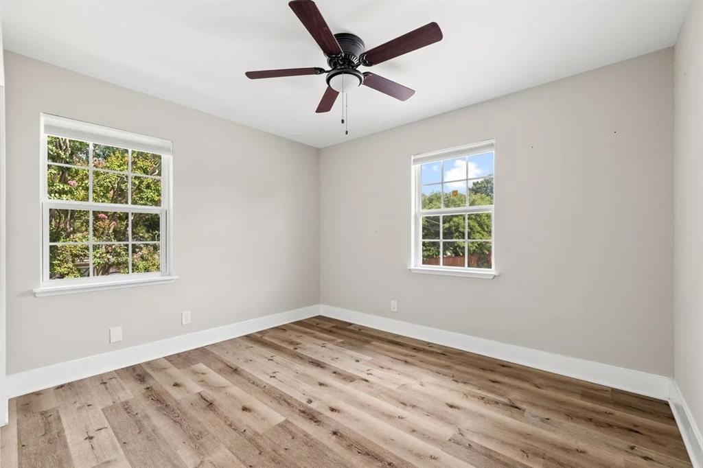 Room featuring wood-finish flooring, dual grid-pattern windows, and a ceiling-mounted fan with integrated lighting
