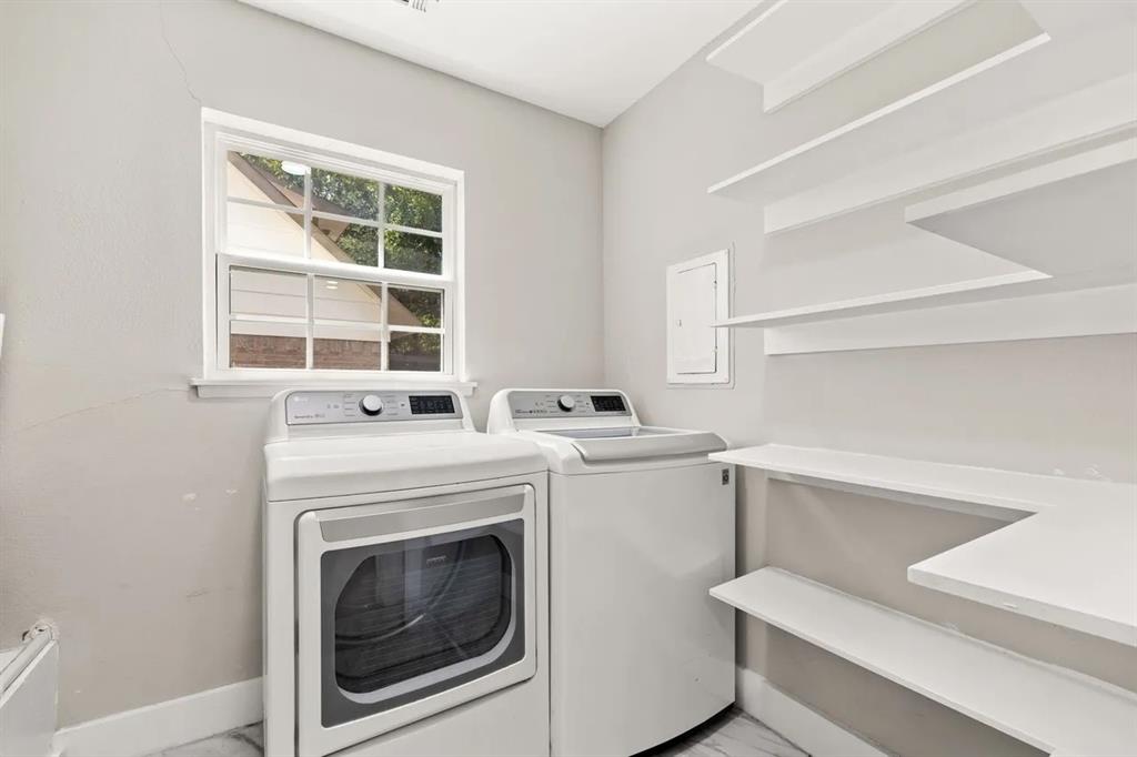 Laundry room featuring built-in wall shelving, a single-hung window with a grid pattern, and light-toned flooring
