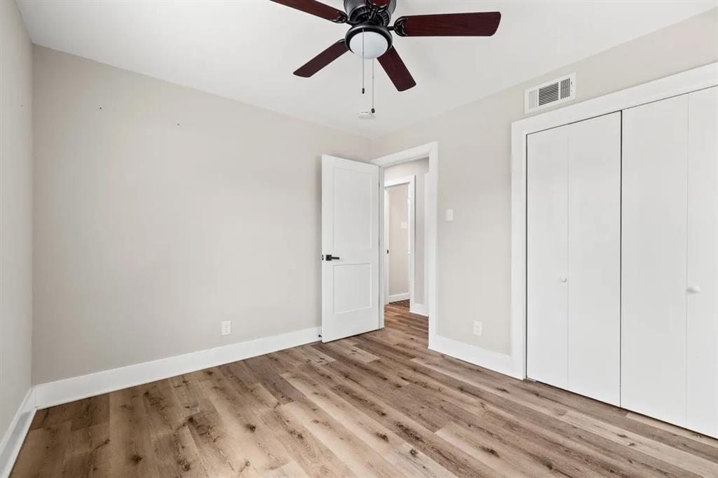 Room featuring wood-finish flooring, a ceiling fan with integrated lighting, neutral wall paint, and a double-door closet
