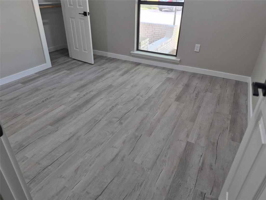 Room featuring wood-finish flooring, a neutral color palette, a single-pane window, and a built-in closet with a panel door