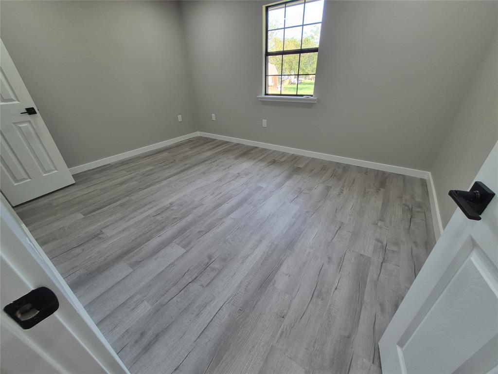 Interior room featuring wood-finish flooring, neutral wall tones, a grid-pattern window, and white paneled doors with matte black hardware