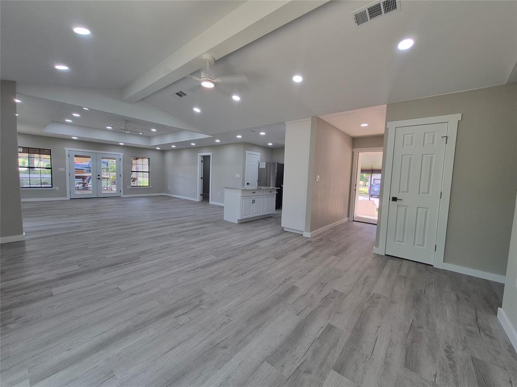 Open-concept interior featuring wood-finish flooring, recessed lighting, vaulted ceilings with dual paddle fans, and a center island with light-toned countertop