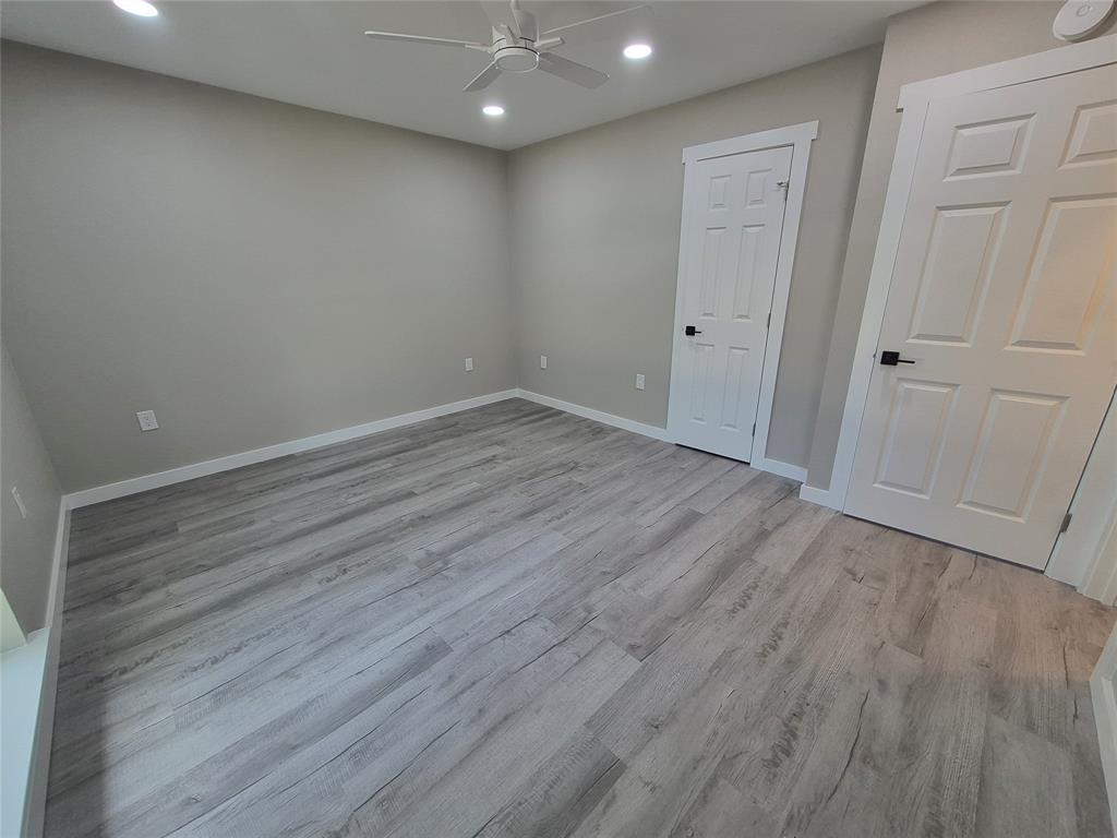 Neutral interior space featuring wood-finish flooring, recessed lighting, a ceiling fan, and six-panel doors with matte black hardware