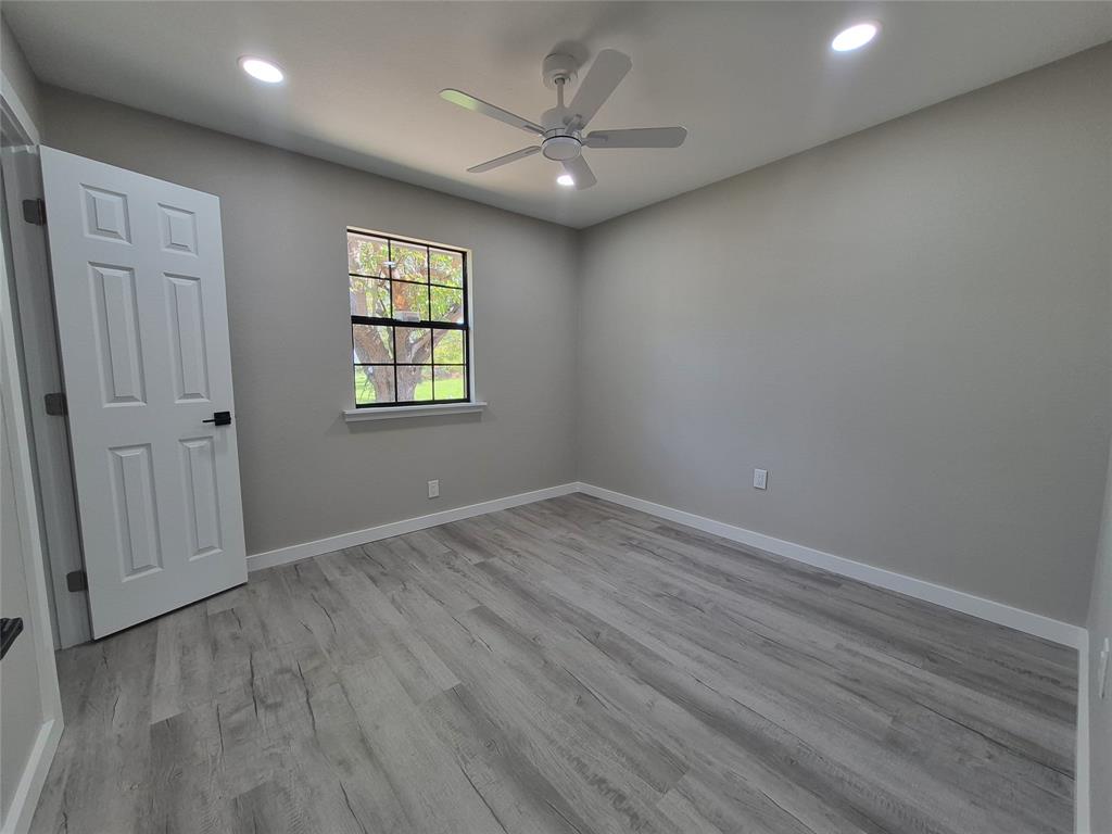 Neutral-toned interior featuring wood-finish flooring, recessed lighting, a ceiling fan with integrated light kit, and a multi-pane window