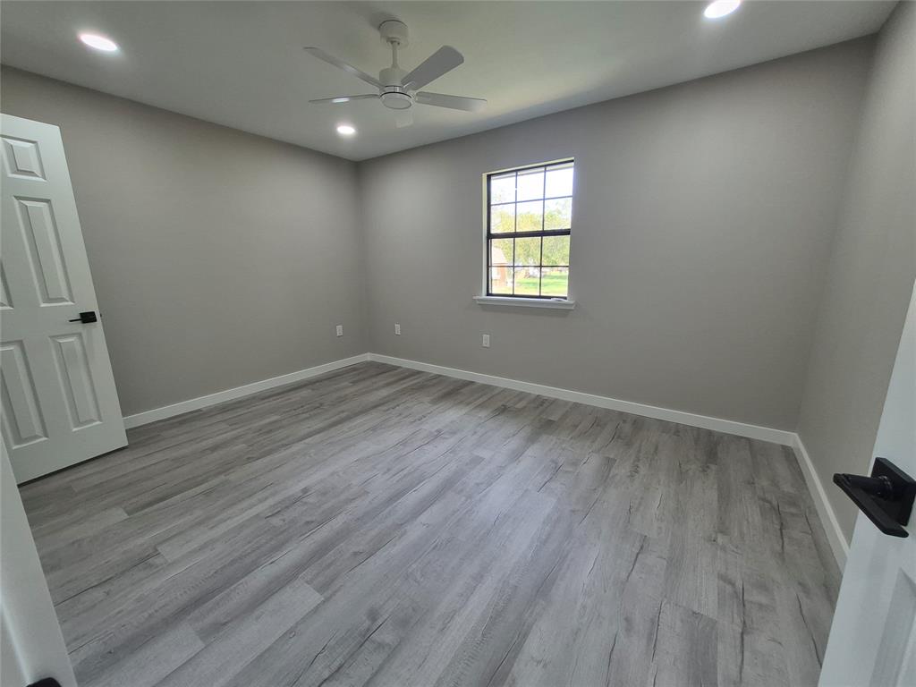 Interior room featuring wood-finish flooring, recessed lighting, a ceiling fan, and a single-hung window with black hardware accents