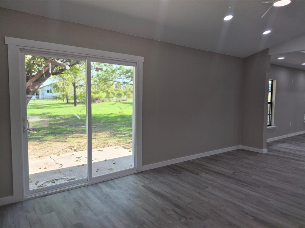 Sliding glass door with white frame, wood-finish flooring, vaulted ceiling, and recessed lighting
