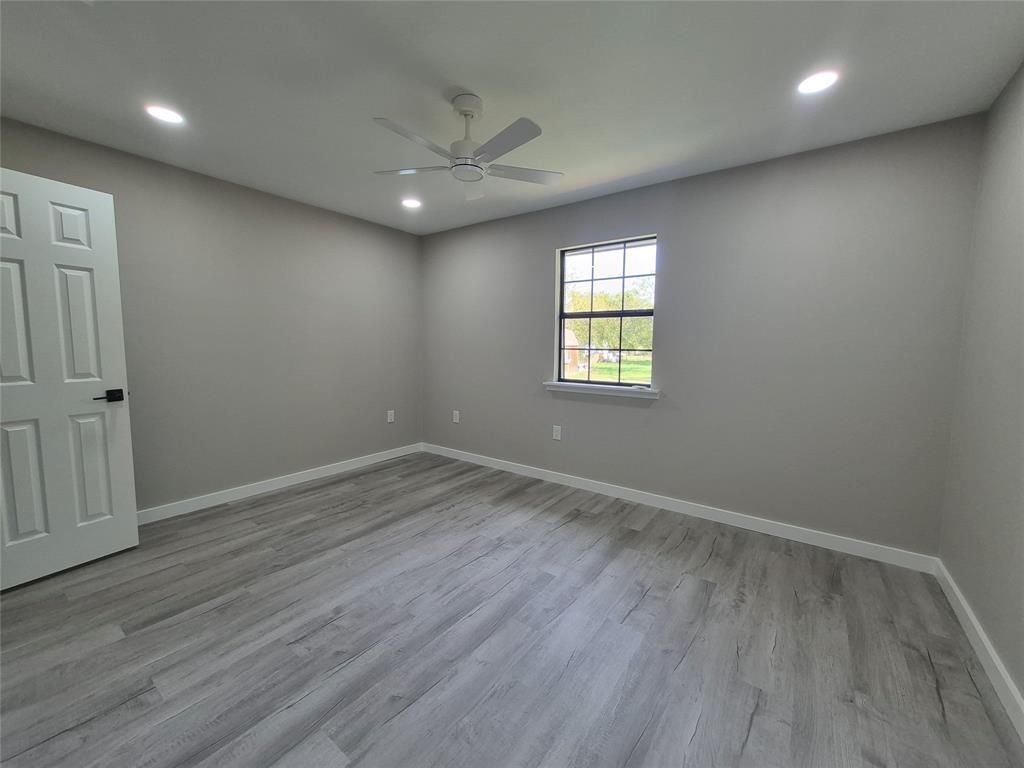 Neutral-toned room featuring wood-finish flooring, recessed lighting, a ceiling fan, and a grid-pane window