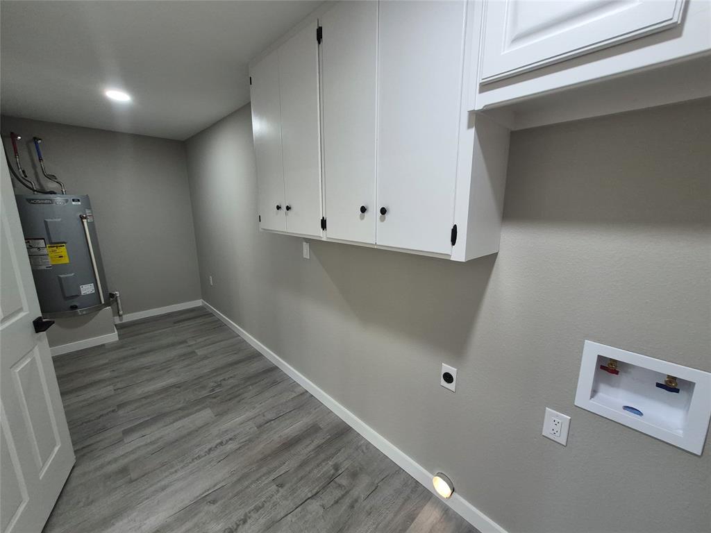 Utility area featuring wood-finish flooring, white wall-mounted cabinetry, recessed lighting, and dedicated water and electrical hookups