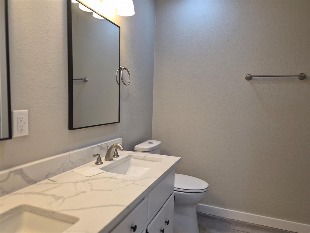 Double vanity featuring stone-surfaced countertops, undermount rectangular sinks, modern framed mirrors, and brushed-finish fixtures