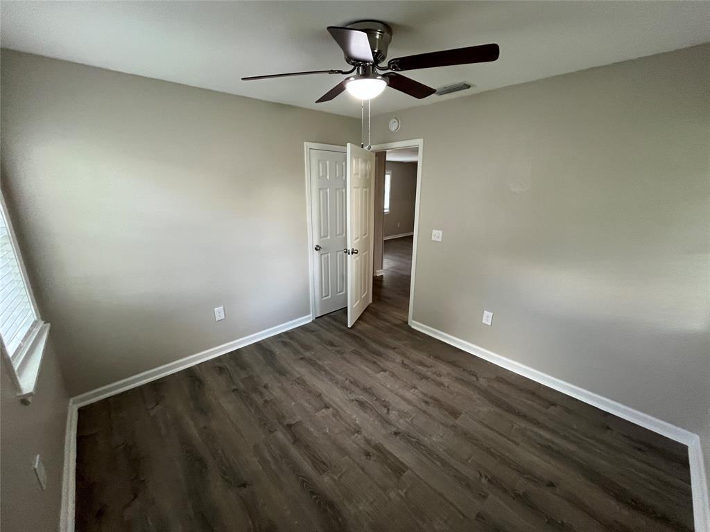 Room interior featuring wood-finish flooring, neutral wall paint, and a ceiling-mounted light fixture with a fan