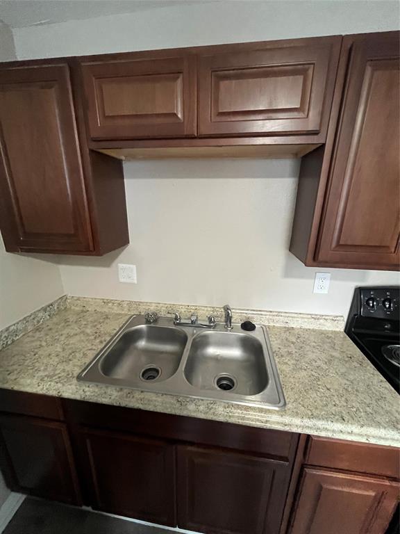 Raised-panel wood cabinetry, laminate countertops, dual-basin stainless steel sink, and chrome finish faucet