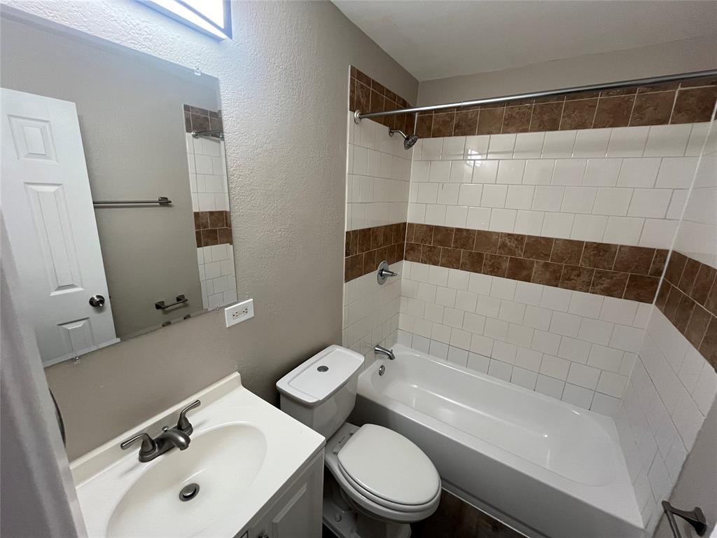 Bathroom featuring a white vanity with an integrated sink, polished chrome faucet, rectangular wall-mounted mirror, and a tub-shower combination with decorative tile inlay
