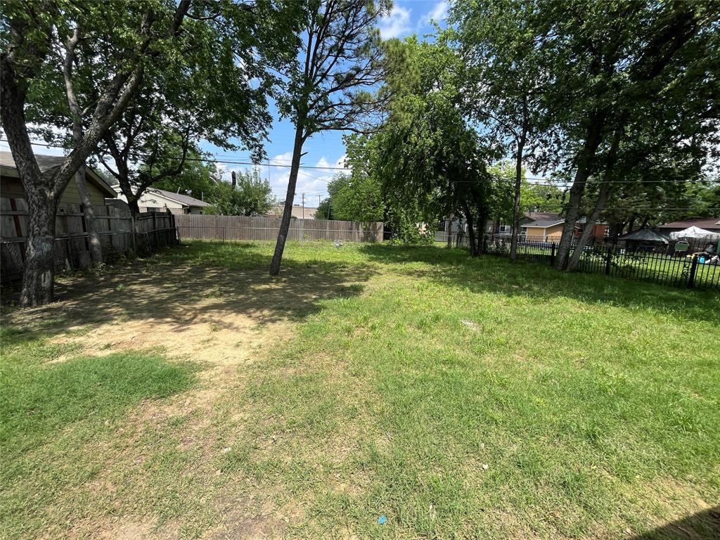 Expansive backyard featuring mature trees and perimeter wood and metal fencing