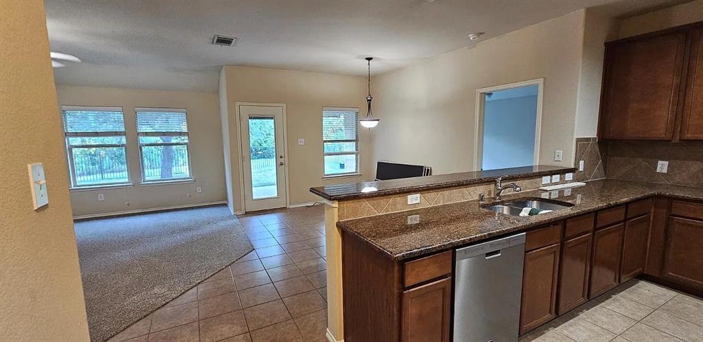 Kitchen featuring a breakfast bar, dark-toned cabinetry, stainless steel dishwasher, tiled flooring, and neutral wall tones
