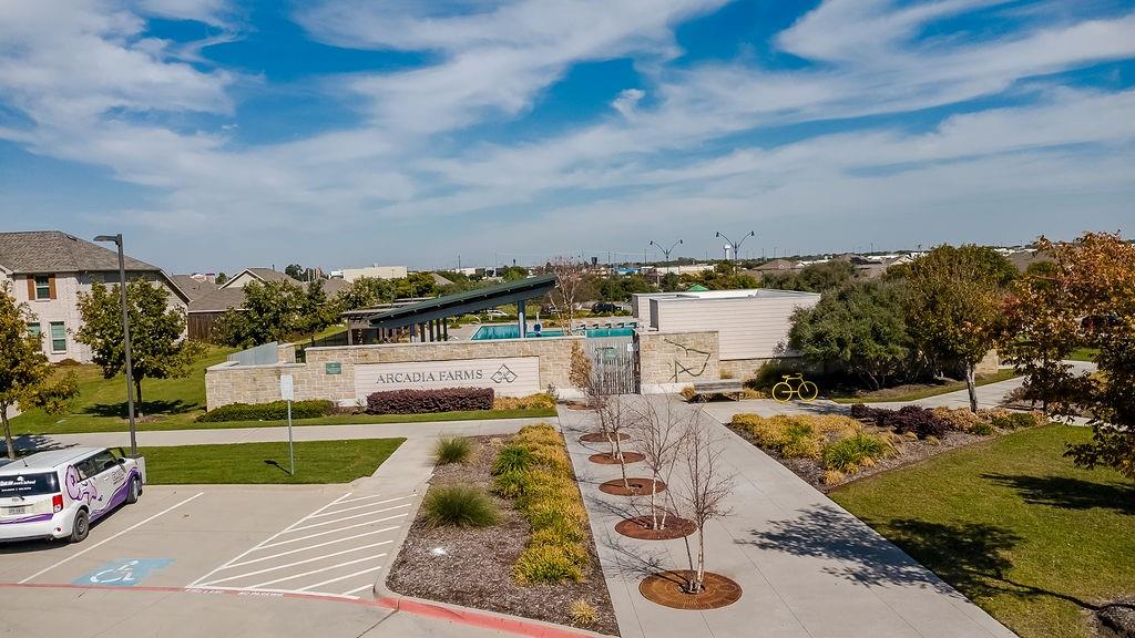 Community recreation area featuring a swimming pool, shaded pergola, paved walkways, and professional landscaping