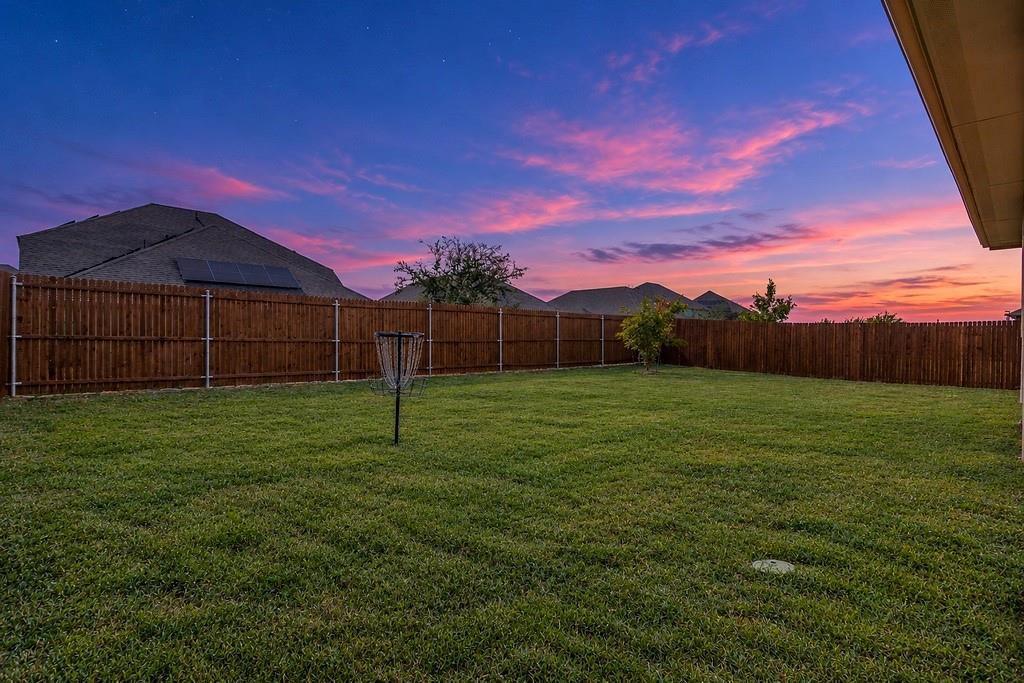 Expansive backyard featuring a sodded lawn and full-perimeter wood privacy fencing