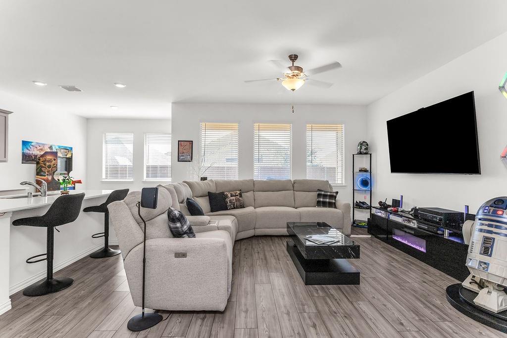 Open concept space featuring vinyl flooring, recessed lighting, a ceiling fan, and large windows with horizontal blinds