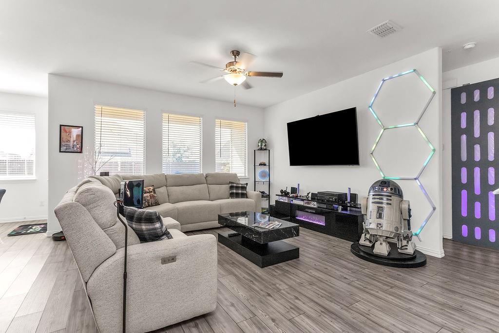 Living area featuring vinyl flooring, a ceiling fan, and multiple windows