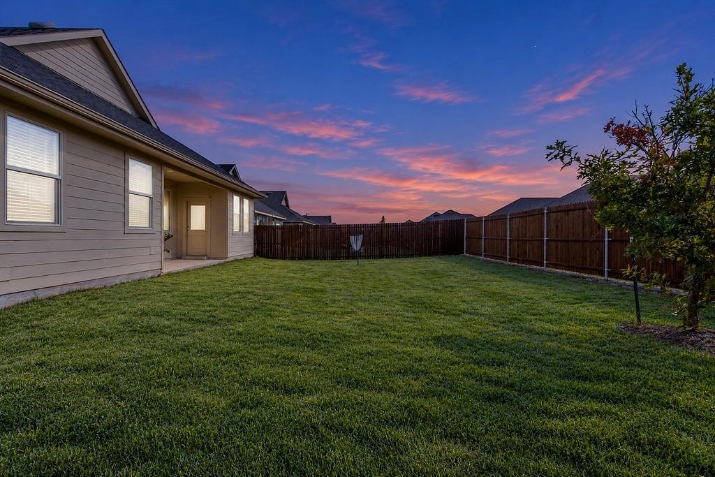 Backyard featuring a grass lawn, horizontal siding, a covered concrete patio, and a wood privacy fence