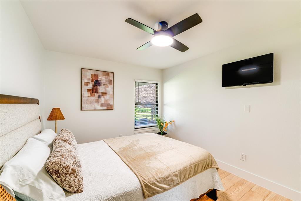 Neutral-toned interior featuring wood-finish flooring, a contemporary ceiling fan with integrated lighting, and a single-pane window with blinds