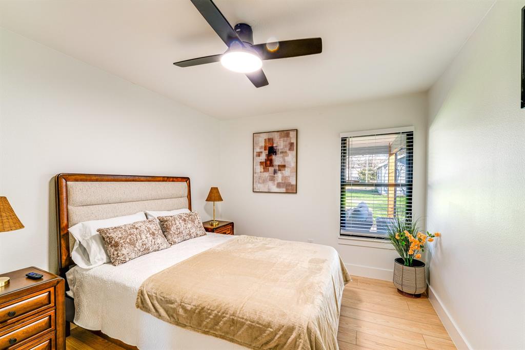 Wood-finish flooring, matte black ceiling fan with integrated lighting, and window featuring horizontal blinds