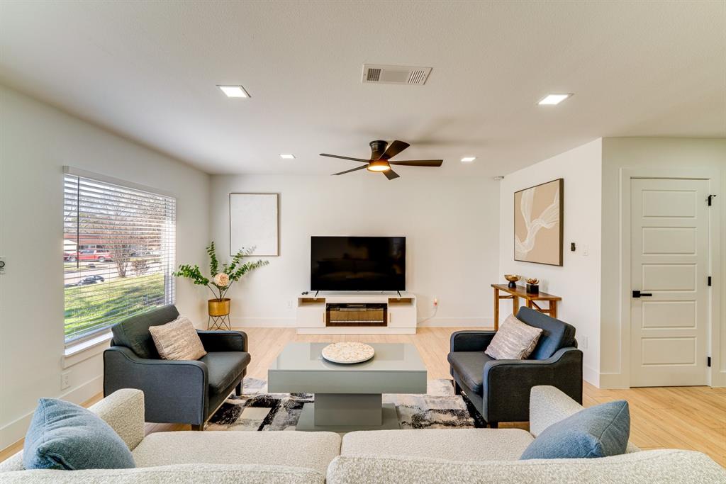 Living area featuring light-toned wood-finish flooring, recessed lighting, a ceiling fan, and a multi-panel door with matte black hardware Living area featuring light-toned wood-finish flooring, recessed lighting, a ceiling fan, and a multi-panel door with matte black hardware