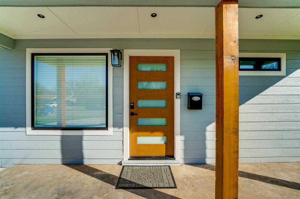 Covered entryway featuring horizontal siding, a natural wood-finish front door with horizontal glass inserts, recessed lighting, and an exposed wooden support post Covered entryway featuring horizontal siding, a natural wood-finish front door with horizontal glass inserts, recessed lighting, and an exposed wooden support post