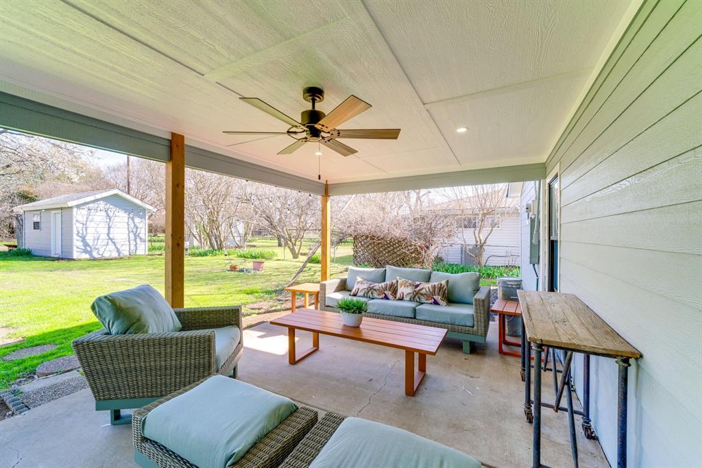 Covered patio featuring a concrete floor, horizontal siding, wood support posts, and a ceiling-mounted fan with integrated lighting