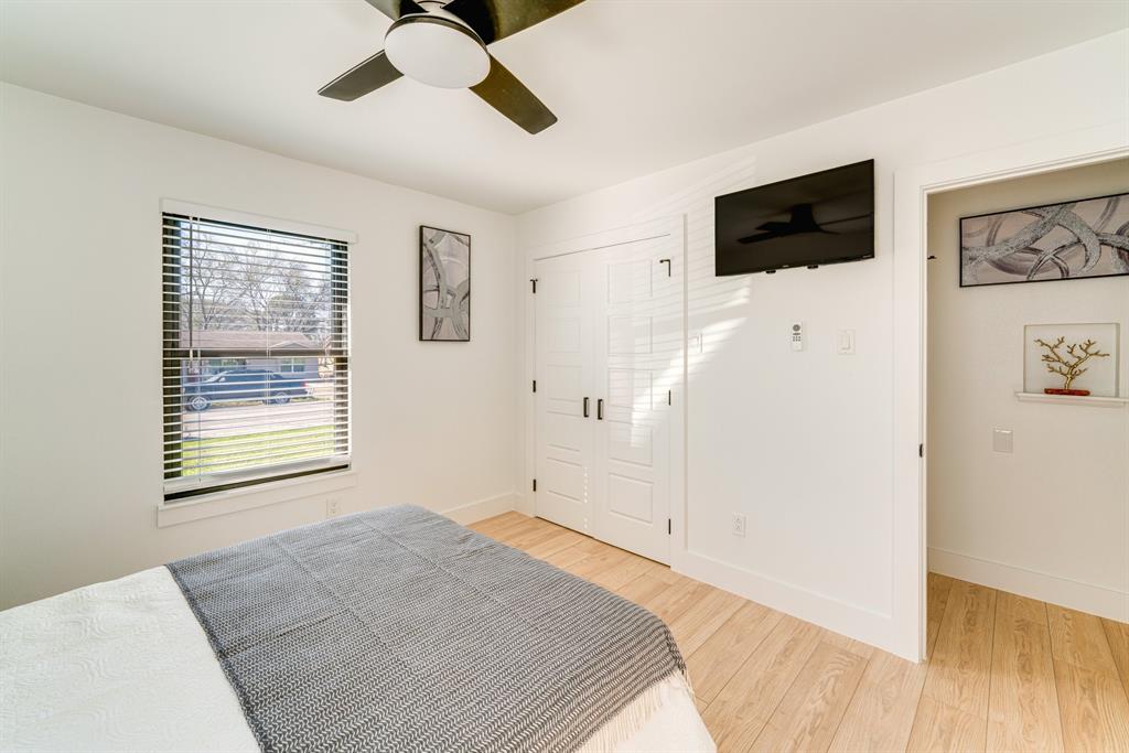 Light-filled room featuring wood-finish flooring, a ceiling fan with integrated lighting, a single-hung window with horizontal blinds, and paneled double closet doors
