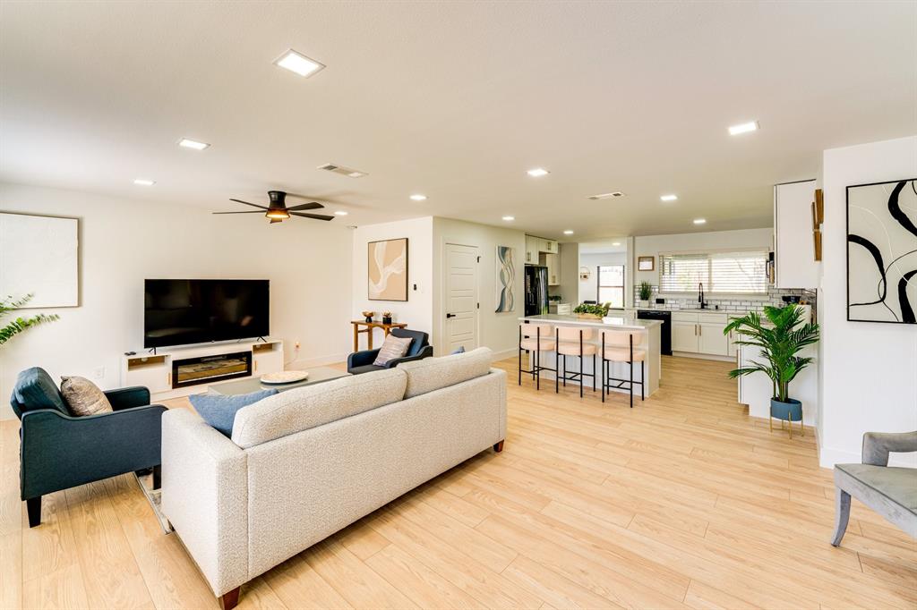 Open-concept interior featuring wood-finish flooring, recessed lighting, and a kitchen island with stone-surface countertop Open-concept interior featuring wood-finish flooring, recessed lighting, and a kitchen island with stone-surface countertop
