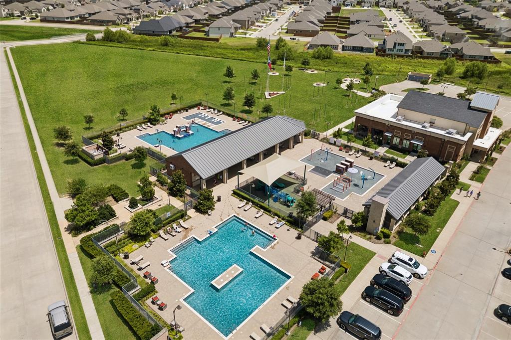 Community amenities featuring two swimming pools, two separate children's play areas, a large open green space, and a clubhouse building with a brick exterior