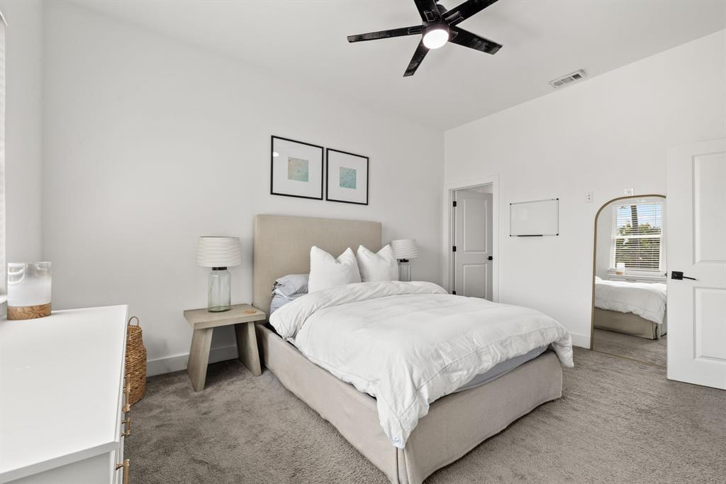 Vaulted ceiling, neutral wall-to-wall carpeting, and matte black ceiling fan with integrated lighting