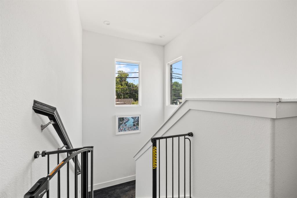 Staircase featuring dark-toned railings, recessed ceiling lighting, and multiple windows providing natural illumination