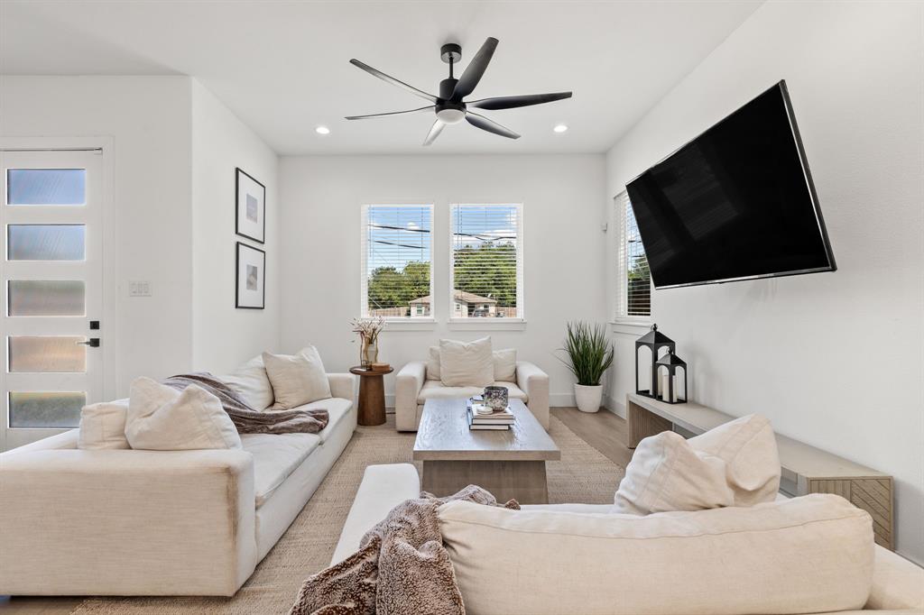 Living area featuring neutral wall paint, multi-paned glass exterior door, recessed lighting, matte black ceiling fan, and double-pane windows Living area featuring neutral wall paint, multi-paned glass exterior door, recessed lighting, matte black ceiling fan, and double-pane windows