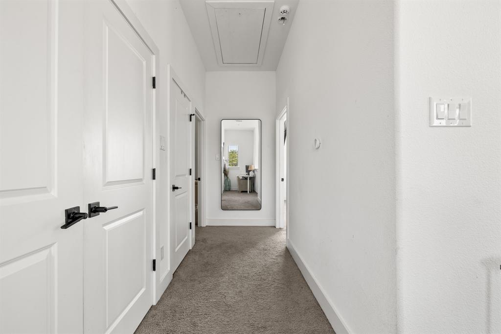 Hallway featuring neutral carpeted flooring, paneled interior doors, and matte black hardware