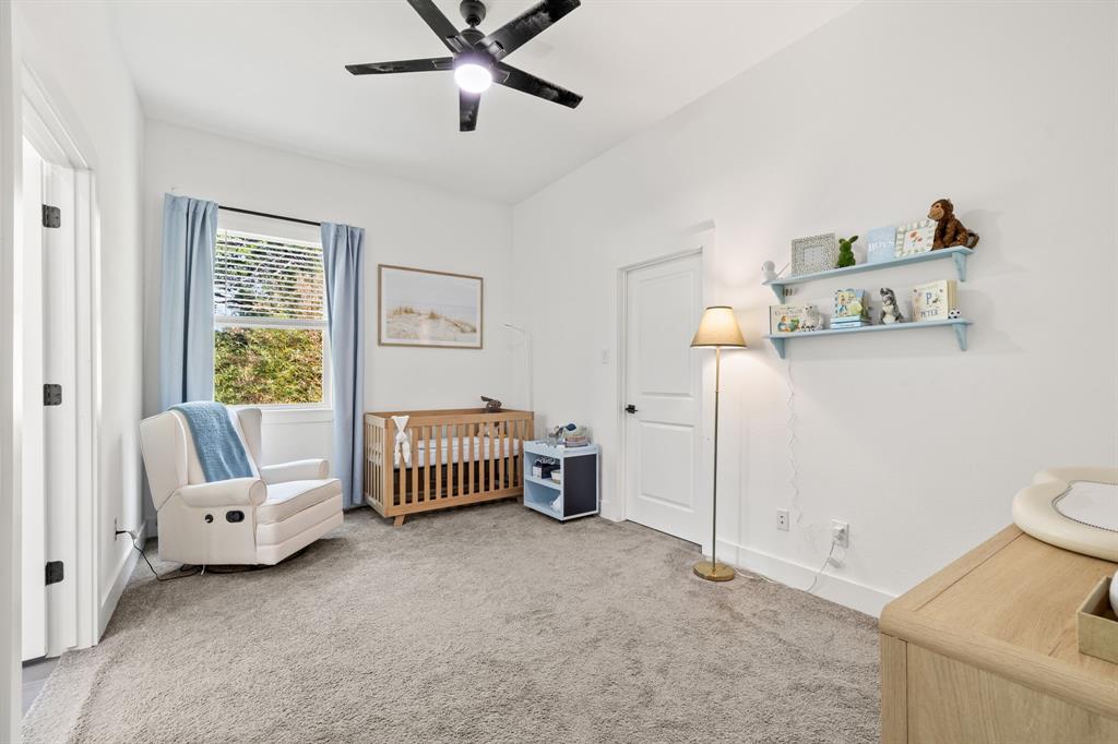 Neutral-toned carpeting, matte black ceiling fan, single-hung window with exterior view, and solid core interior door with matte black hardware